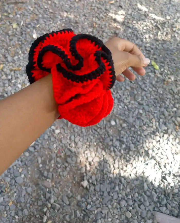 Red and black crochet scrunchie worn on a wrist